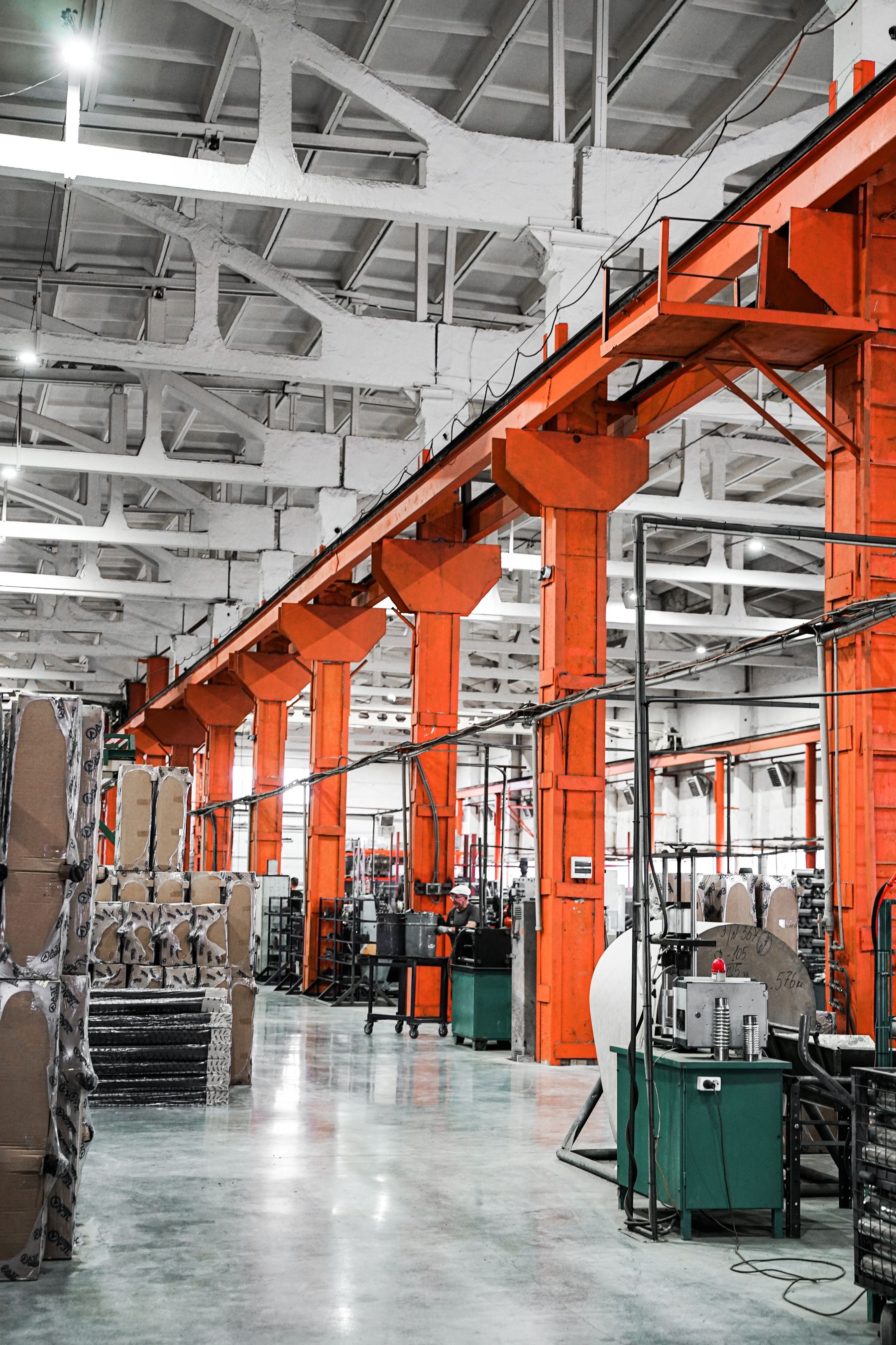 Produktionshalle mit Maschinen, Werkstücken und orangefarbener Tragstruktur